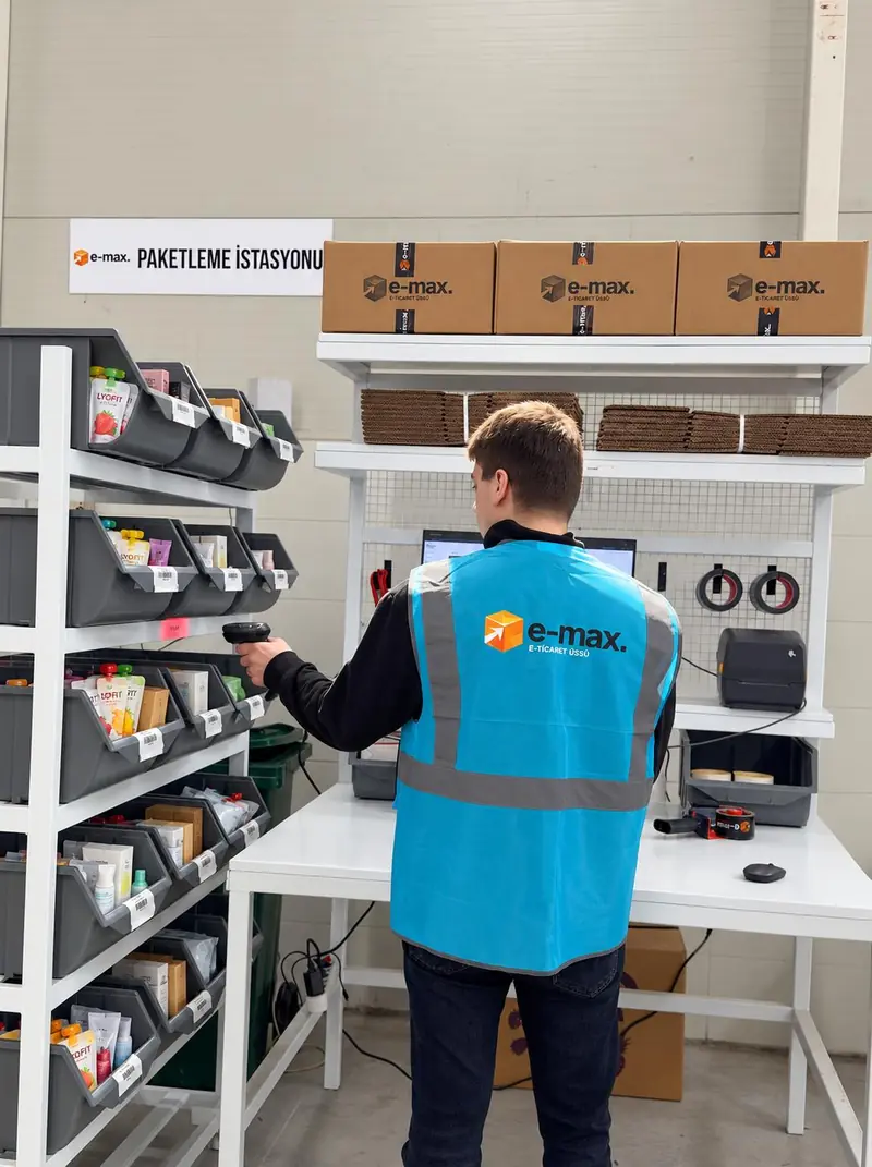 Paketleme istasyonunda çalışan, raftaki ürünü okuyucuyla okutuyor